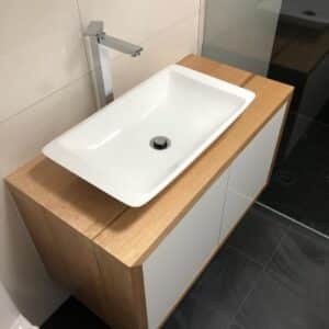 Light brown vanity with white sink and silver taps in bathroom after broken pipes were repaired