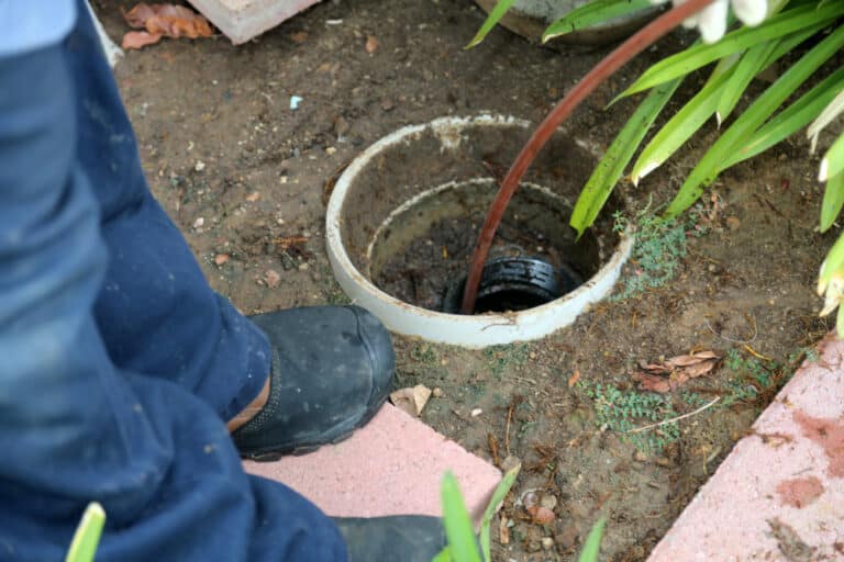 A plumber uses a sewer snake to clean blockage in a sewer line.