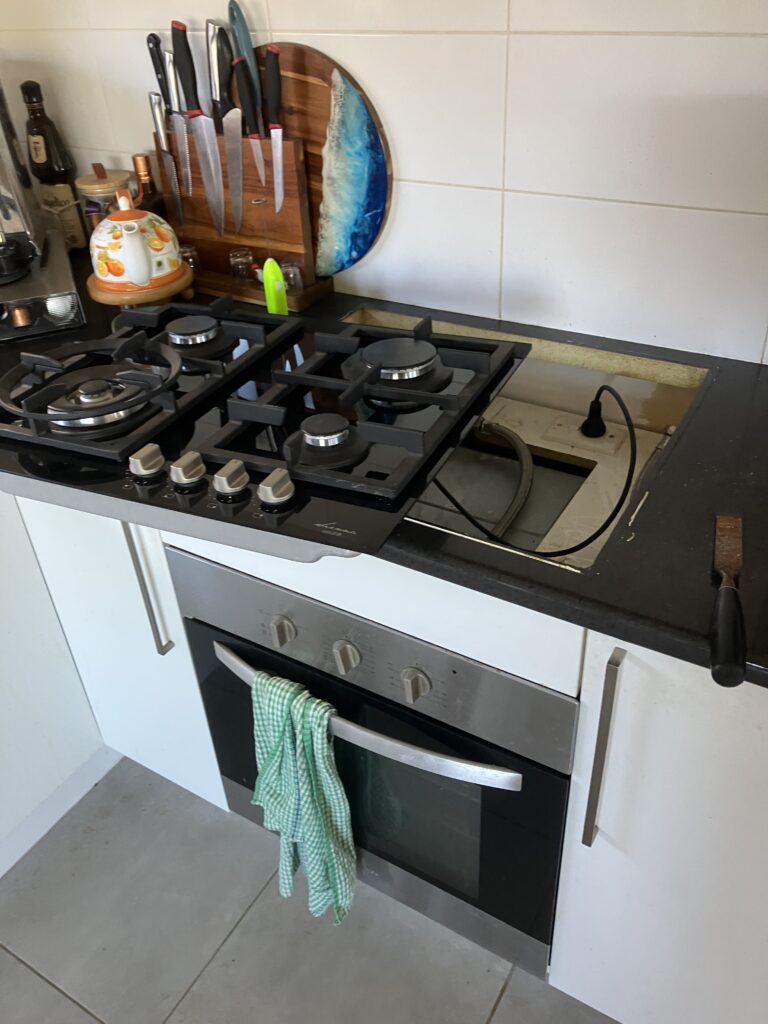 Gas cooktop installation in progress above an under-bench oven in a kitchen